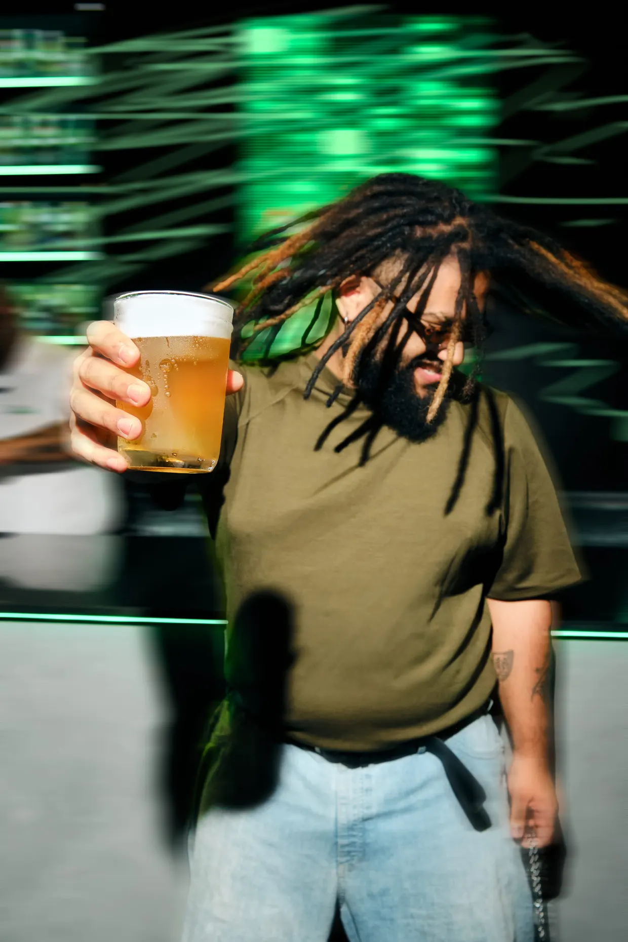 Pessoa segura um copo de cerveja durante uma festa, com efeito de movimento.