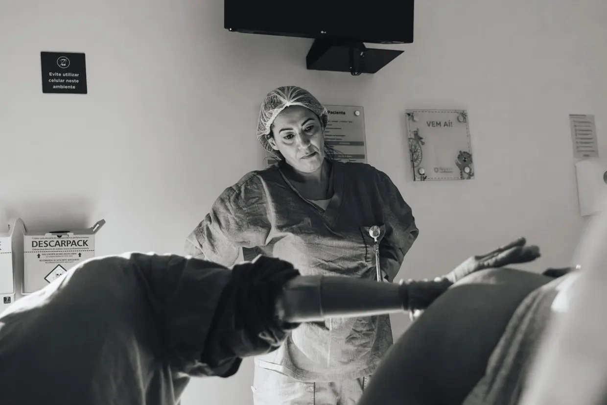 Fotografia em preto e branco de acompanhante junto à cama hospitalar.