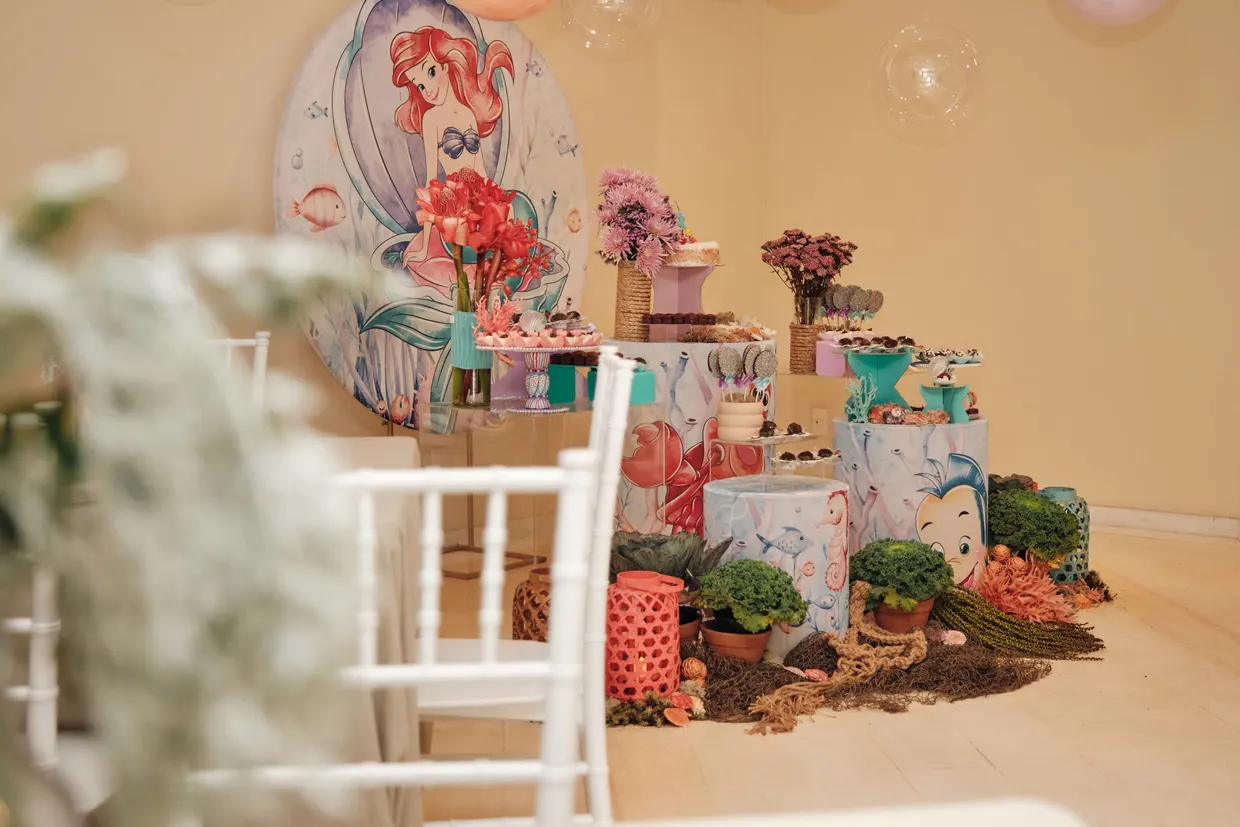 Mesa de festa decorada com flores, doces e elementos de fundo do mar.