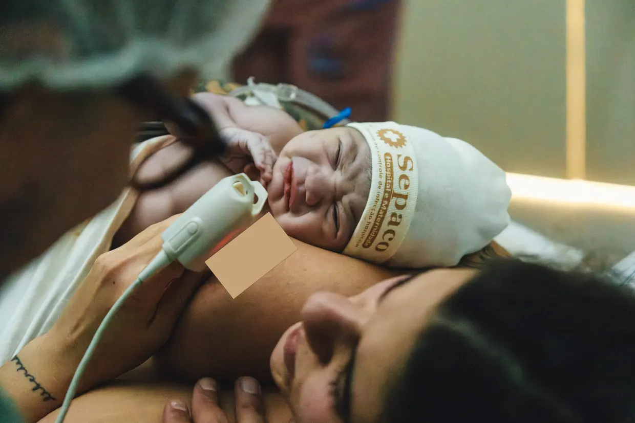 Close de mãe sorrindo com o recém-nascido junto ao rosto.
