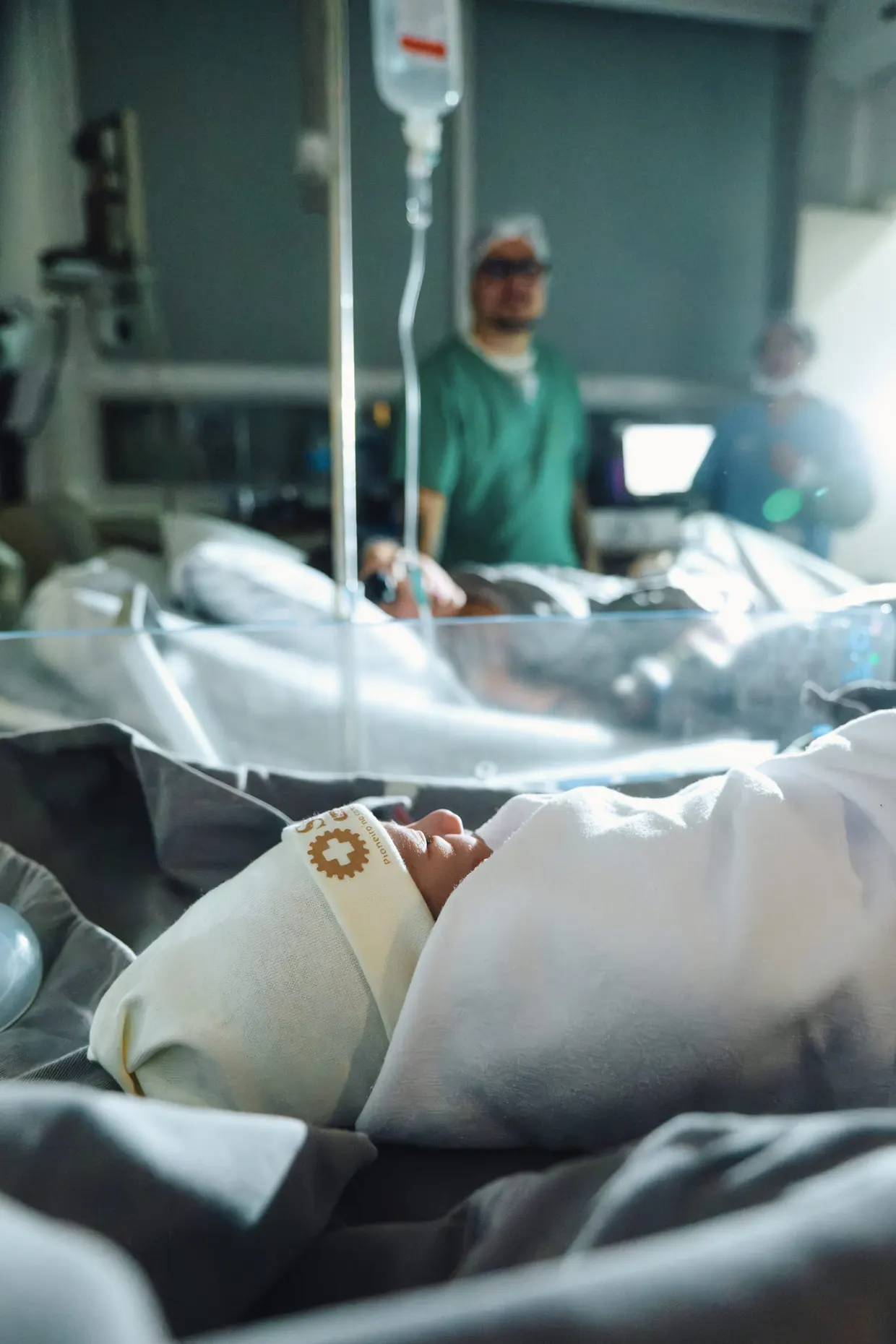 Cena do quarto hospitalar com a cama em primeiro plano e acompanhante ao fundo.